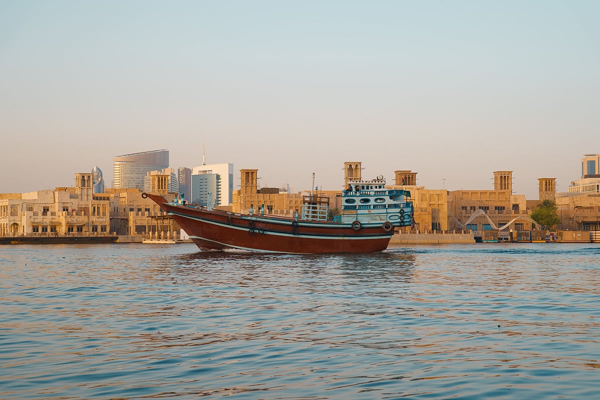 A traditional wooden dhow on Dubai Creek in warm evening light